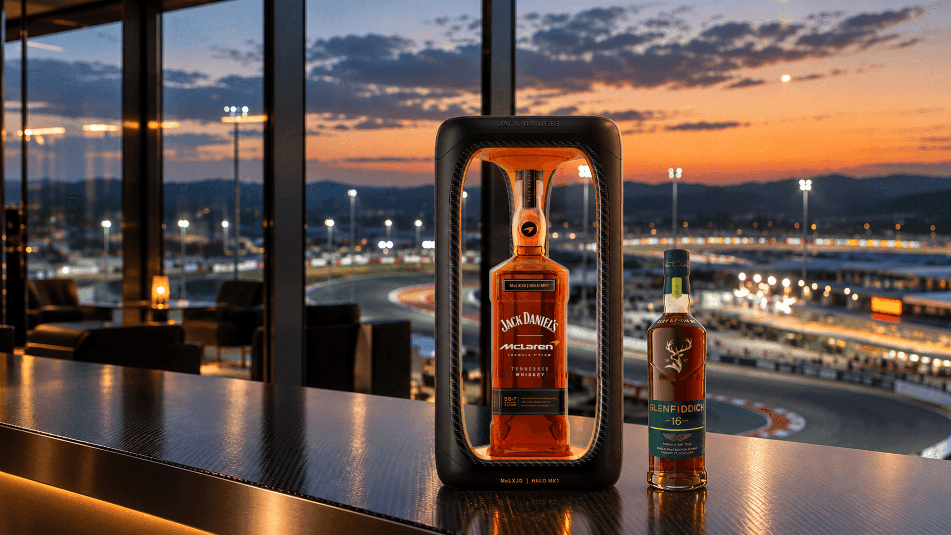 Jack Daniel's McLaren Halo MK1 en su marco expositor con forma de Halo junto a un Glenfiddich 16 años edición Aston Martin Formula One Team sobre una barra de fibra de carbono con vistas a un circuito al atardecer