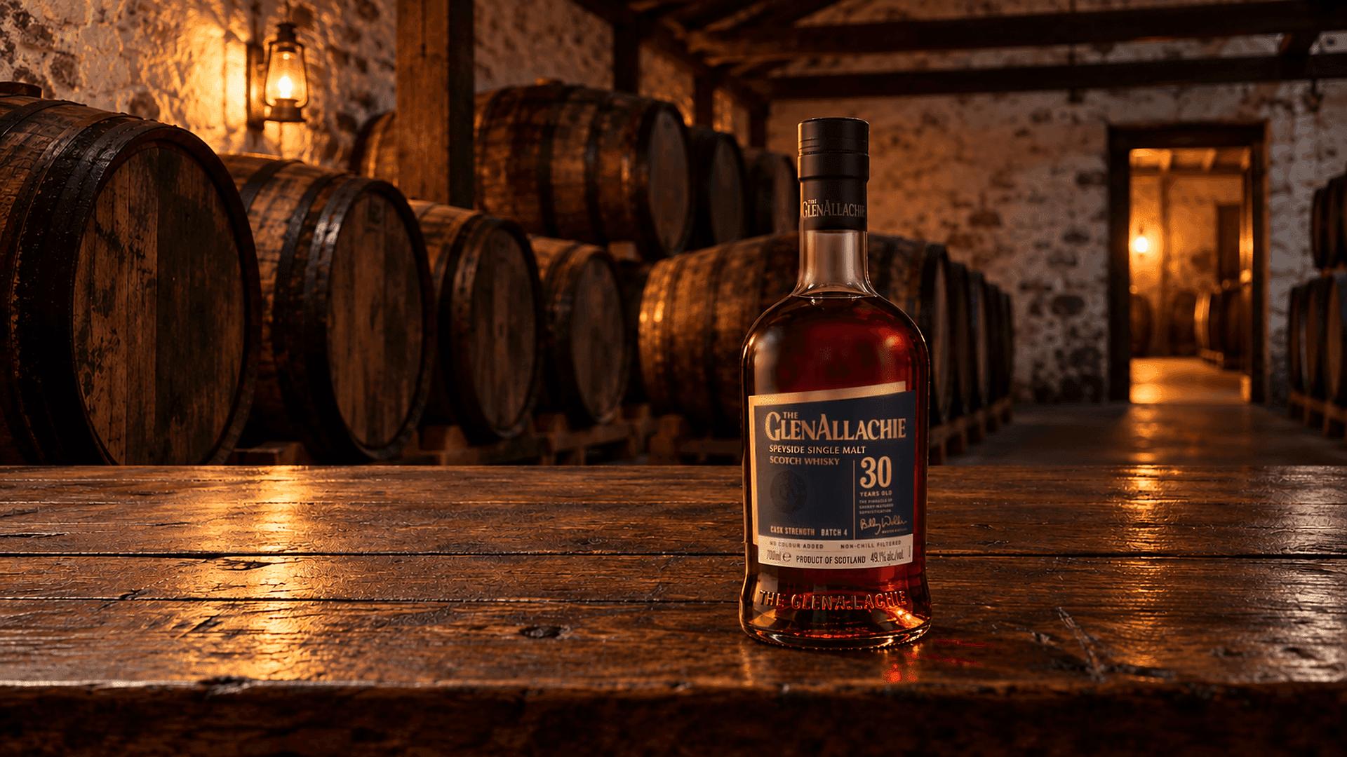 GlenAllachie 30 anni Cask Strength su un tavolo di rovere scuro in un vecchio magazzino dello Speyside con file di botti di sherry e una lanterna accesa