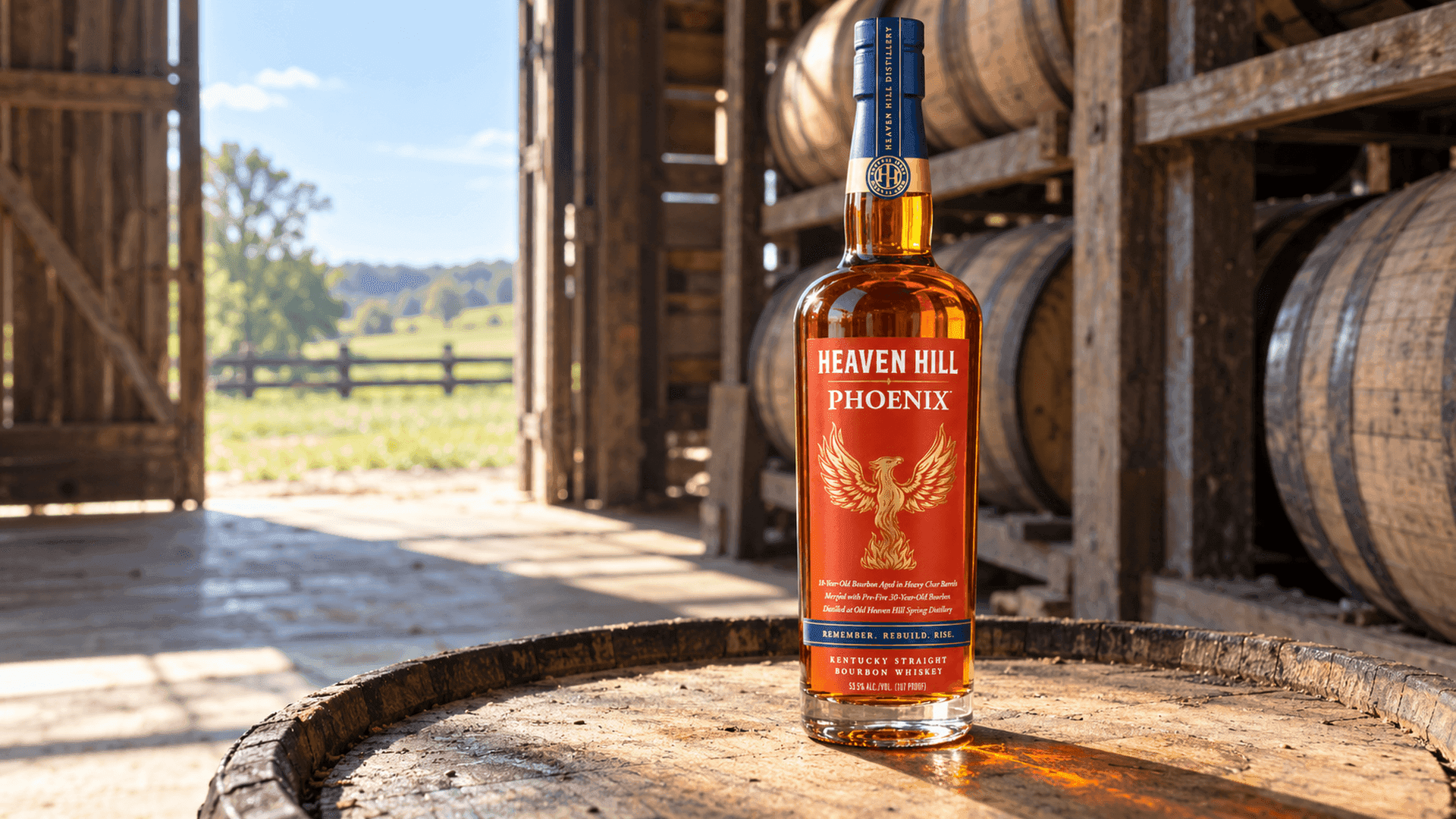 Heaven Hill Phoenix bottle standing on a barrel at the open door of a Kentucky rickhouse in bright daylight