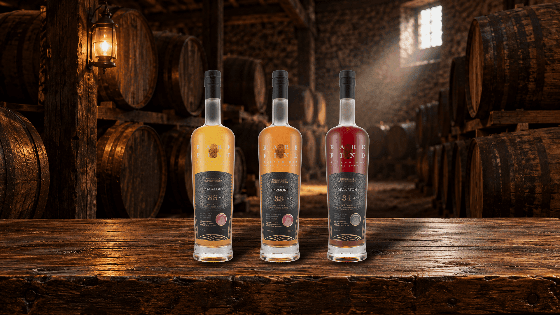 Rare Find Macallan 36, Tormore 38 e Deanston 34 Years Old su un vecchio tavolo di rovere in un magazzino dunnage in penombra con botti di sherry